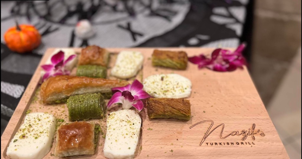 Assorted Turkish baklava and desserts with pistachios on a wooden serving board