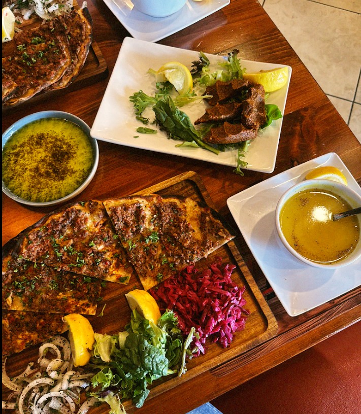 Turkish pide and lahmacun spread with cig kofte, lentil soup, and fresh herbs